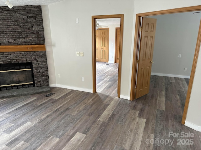 unfurnished living room featuring baseboards, a fireplace, visible vents, and wood finished floors