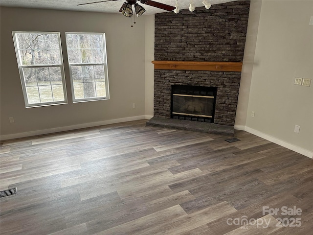 unfurnished living room with visible vents, a fireplace, baseboards, and wood finished floors