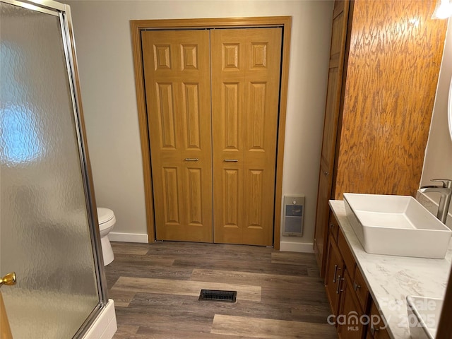 bathroom with double vanity, visible vents, a shower stall, and wood finished floors