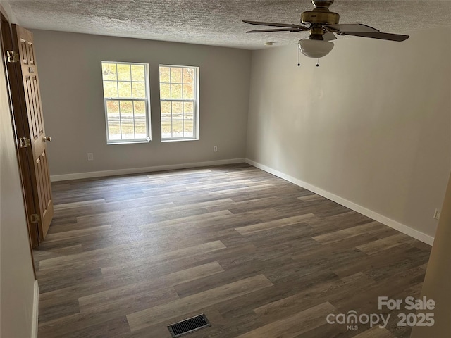 spare room featuring baseboards, visible vents, dark wood-style flooring, and a textured ceiling