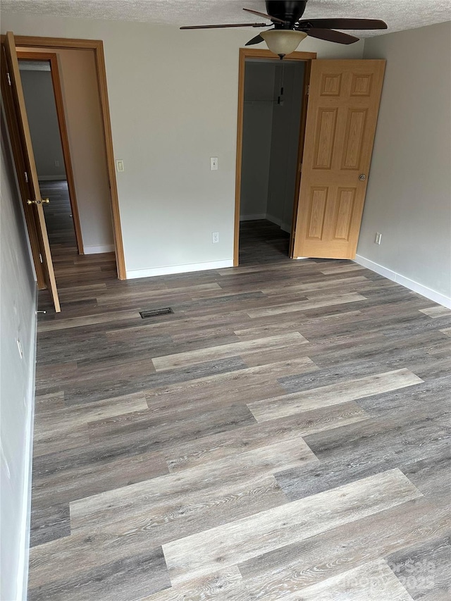 interior space featuring a ceiling fan, baseboards, visible vents, and wood finished floors