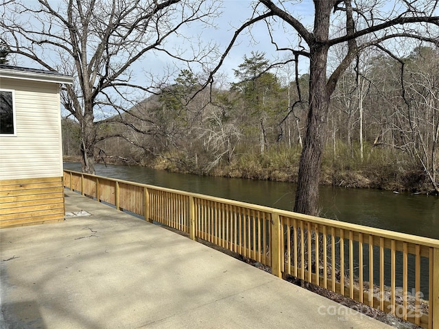 wooden terrace featuring a water view and a view of trees