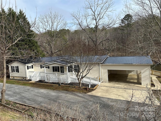 view of front of house with driveway, covered porch, and metal roof