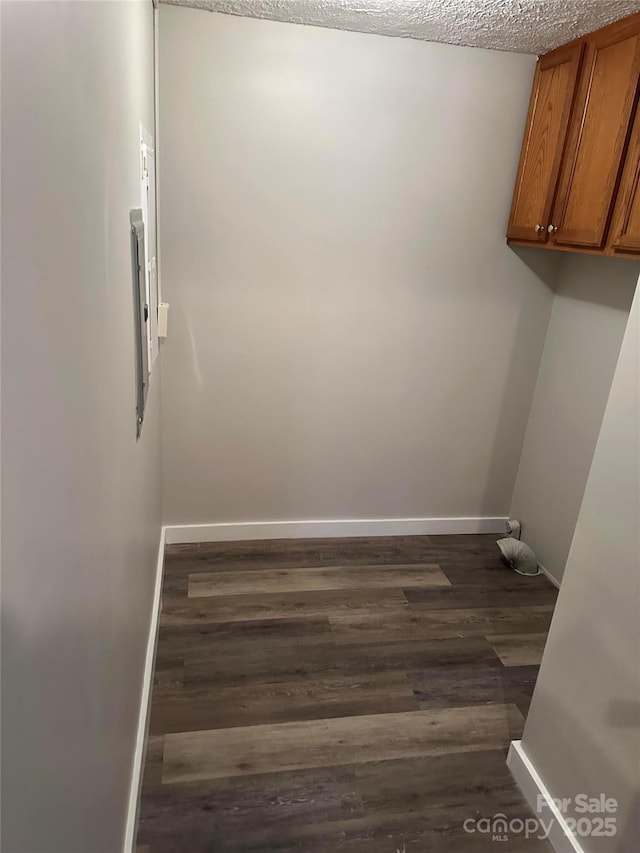 laundry room featuring dark wood-style flooring, cabinet space, and baseboards