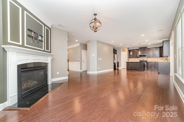 3004 Fallondale Rd, Waxhaw, NC 28173 - unfurnished living room with dark wood-style flooring, a chandelier, baseboards, a glass covered fireplace, and recessed lighting