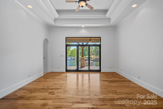 spare room with ornamental molding, arched walkways, a raised ceiling, and ceiling fan