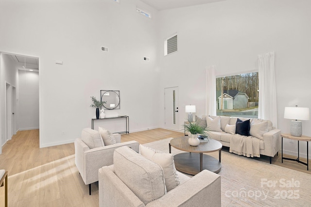 living room with light wood-type flooring and a towering ceiling