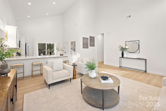 living room featuring light hardwood / wood-style floors and a towering ceiling