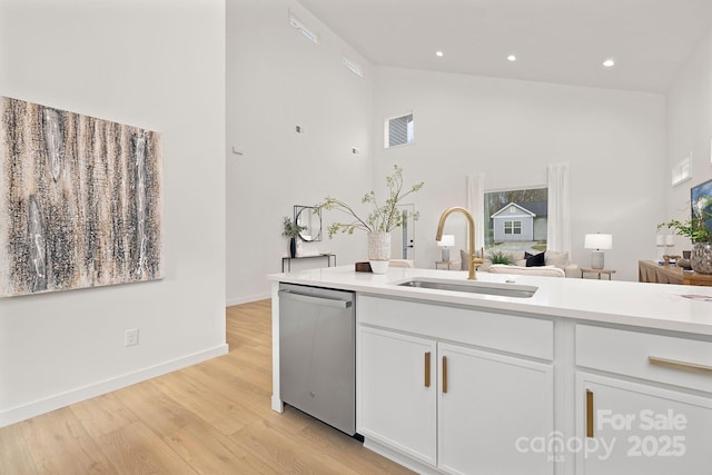 kitchen with white cabinetry, light hardwood / wood-style floors, sink, dishwasher, and high vaulted ceiling