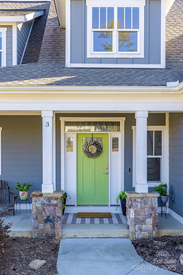 view of exterior entry featuring a porch and a shingled roof