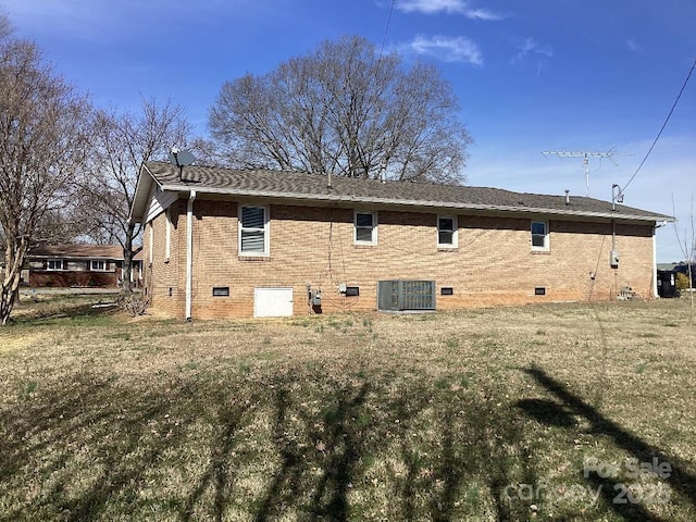 rear view of house featuring cooling unit and a lawn