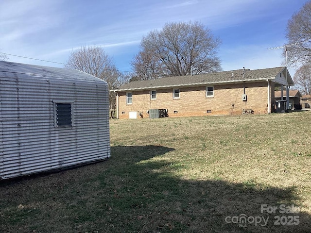 back of property with an outbuilding, central AC, and a yard