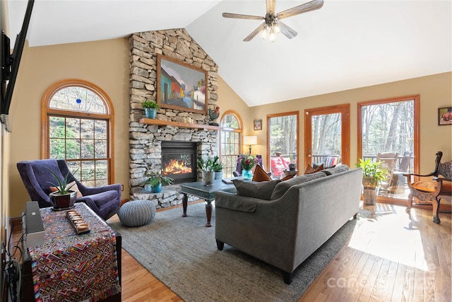 living room with a fireplace, high vaulted ceiling, a wealth of natural light, and wood finished floors