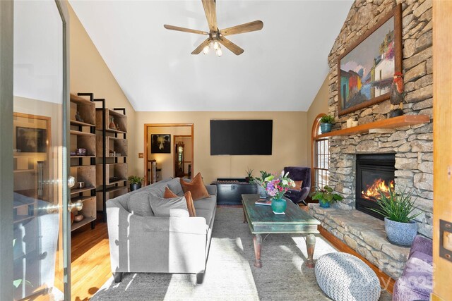 living area with lofted ceiling, ceiling fan, a fireplace, and wood finished floors