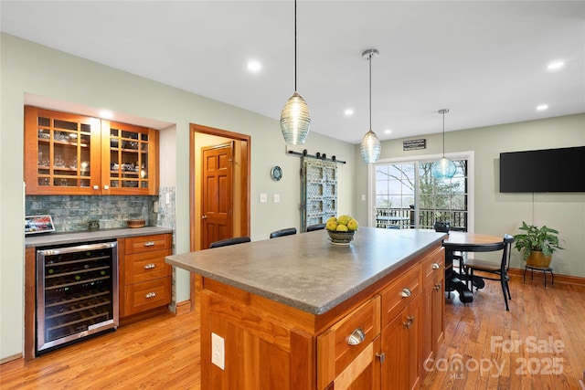 kitchen with glass insert cabinets, wine cooler, brown cabinets, and a kitchen island