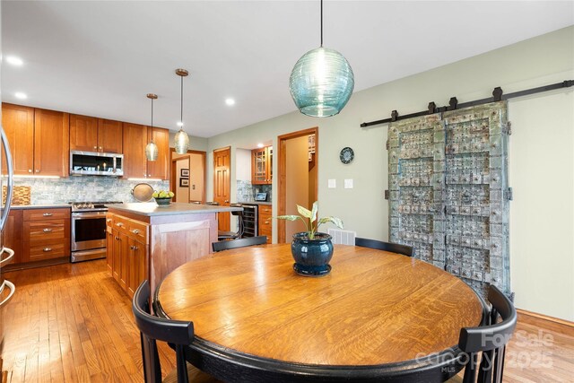 dining room featuring recessed lighting, visible vents, a barn door, light wood-type flooring, and beverage cooler