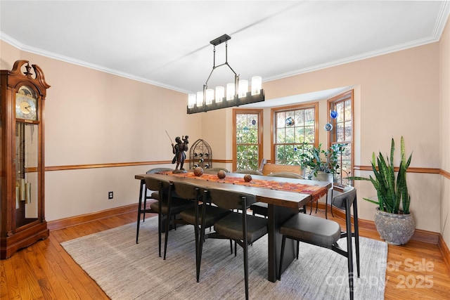 dining space with light wood-style floors, ornamental molding, baseboards, and an inviting chandelier