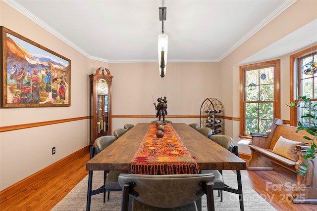 dining room featuring baseboards, crown molding, and light wood finished floors