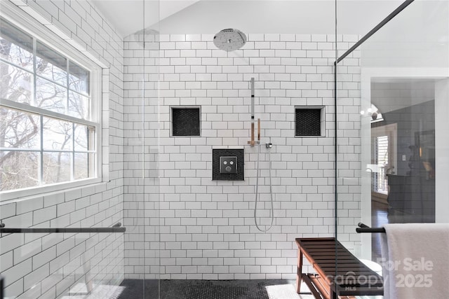 bathroom featuring lofted ceiling and tiled shower