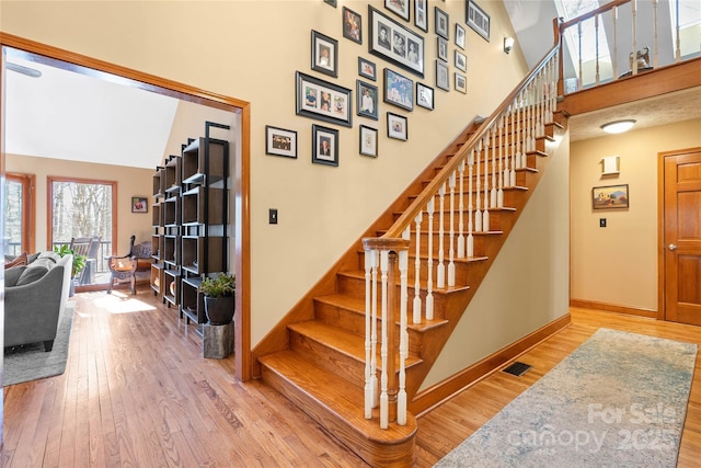 staircase with visible vents, baseboards, and wood finished floors