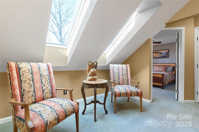 living area featuring baseboards, vaulted ceiling with skylight, and light colored carpet