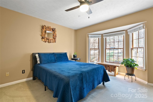 bedroom featuring a ceiling fan, light carpet, a textured ceiling, and baseboards