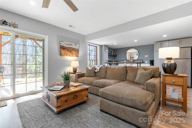 living area featuring a healthy amount of sunlight, light wood finished floors, visible vents, and recessed lighting