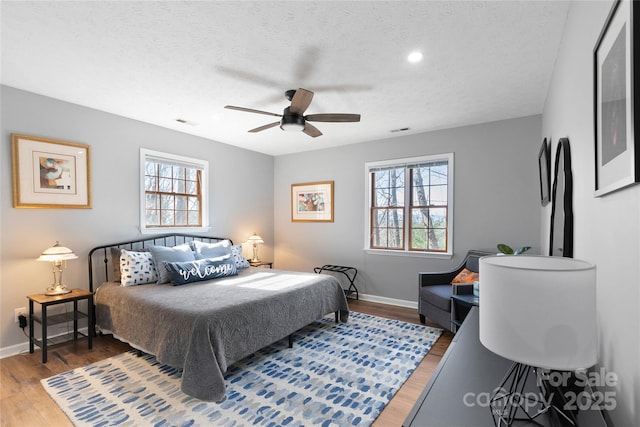 bedroom featuring multiple windows, wood finished floors, and baseboards