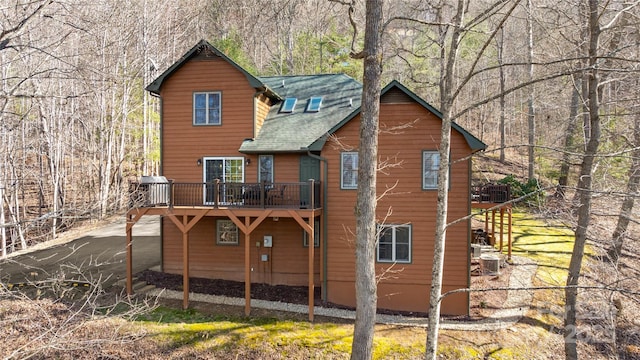 rear view of house featuring roof with shingles and a wooden deck