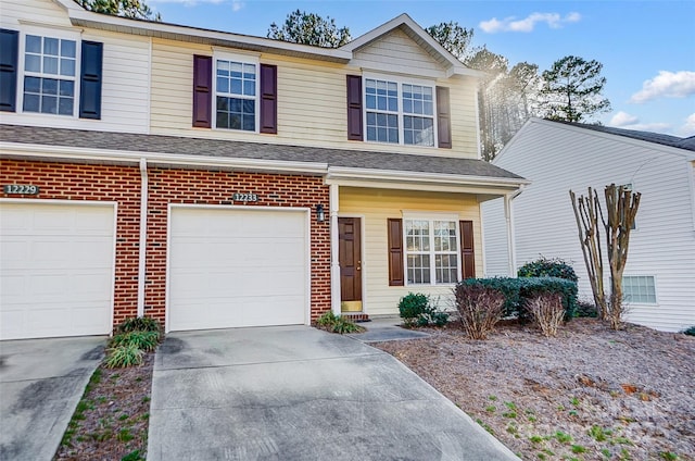 view of front of property featuring a garage, driveway, brick siding, and a shingled roof