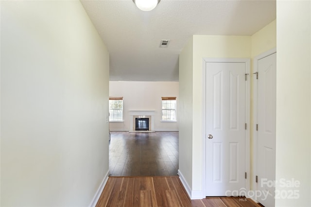 corridor with a textured ceiling and wood-type flooring