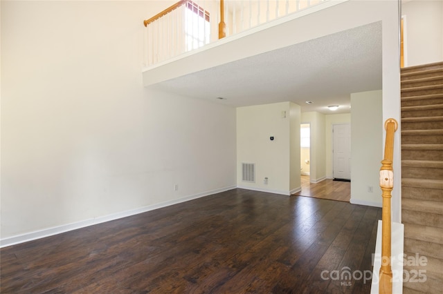 unfurnished room with hardwood / wood-style flooring and a towering ceiling