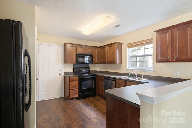 kitchen with kitchen peninsula, black appliances, sink, a textured ceiling, and dark wood-type flooring