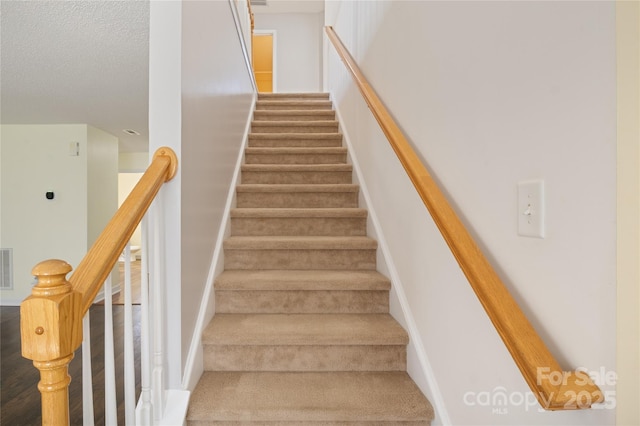 staircase featuring a textured ceiling