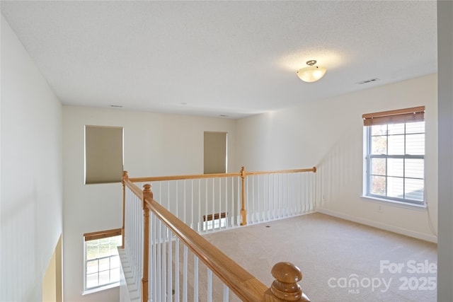 hall featuring carpet flooring and a textured ceiling