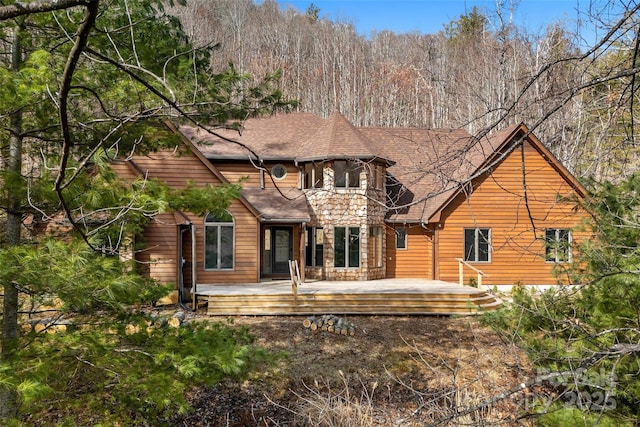 rear view of property with a deck and roof with shingles