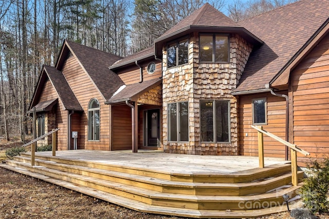 rear view of property with a shingled roof and a deck