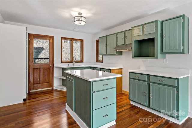 kitchen featuring green cabinetry, dark wood-style floors, a center island, light countertops, and a sink