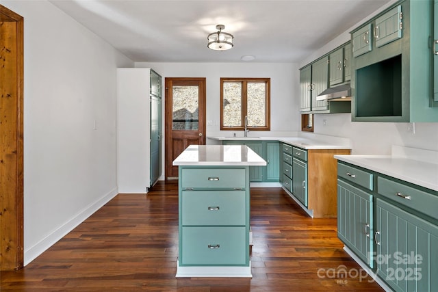 kitchen featuring a sink, light countertops, a kitchen island, and green cabinetry