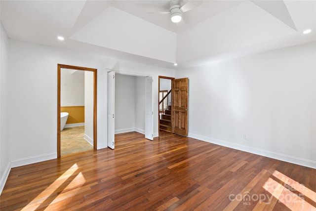 empty room with baseboards, ceiling fan, dark wood-type flooring, a tray ceiling, and recessed lighting