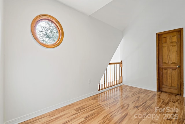 interior space with vaulted ceiling, light wood finished floors, and baseboards