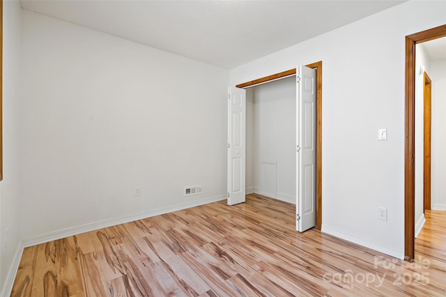 unfurnished bedroom with light wood-style floors, baseboards, visible vents, and a closet