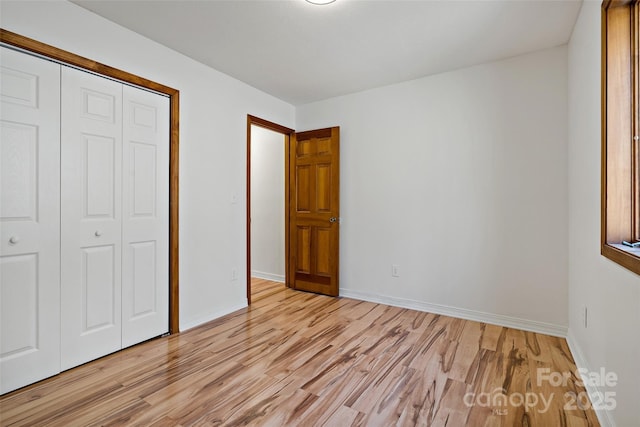 unfurnished bedroom with light wood finished floors, baseboards, and a closet