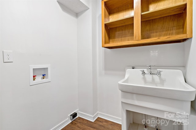 laundry room featuring washer hookup, baseboards, and wood finished floors