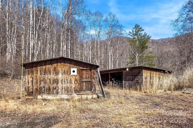 view of outdoor structure featuring an outbuilding, a mountain view, and a view of trees