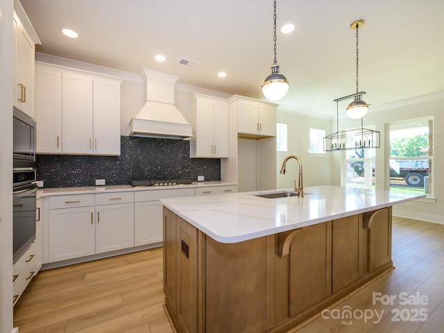 kitchen featuring custom exhaust hood, tasteful backsplash, cooktop, stainless steel oven, and a sink