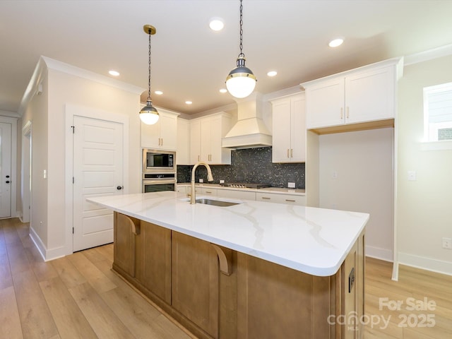 kitchen featuring oven, a sink, premium range hood, light wood finished floors, and built in microwave