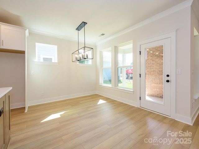 unfurnished dining area featuring baseboards, a chandelier, light wood-style flooring, crown molding, and visible vents