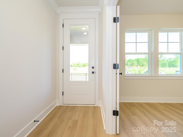 doorway with light wood finished floors and baseboards