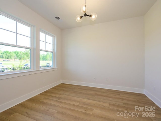 unfurnished room with light wood-style flooring, a chandelier, baseboards, and visible vents